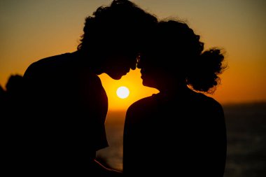 Arka planda güneş olan siluetli genç bir çift. Aşık insanlar.