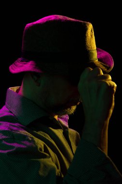 Şapkalı ve güneş gözlüklü gizemli adam. Karanlık stüdyoda portre.