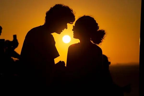 Young couple in silhouette, in late afternoon. Sunset in the background.