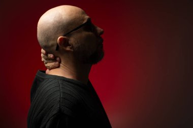 Yakışıklı, kel ve sakallı, güneş gözlüklü, ciddi ve kendine güvenen bir adam. Kırmızı arkaplanda izole.