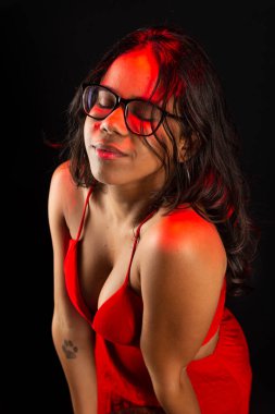 Güzel esmer bir kadının yarı kapalı portresi, reçeteli gözlük takıyor ve kırmızı elbiseler giyiyor. Siyah arkaplanda izole.