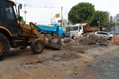 Salvador, Bahia, Brezilya - 05 Ocak 2024: Bahia 'nın Salvador kentindeki ticari bölgede Conceicao da Praia caddesindeki yeniden inşa çalışmasında taşları taşıyan Backhoe traktörü.