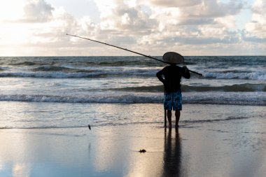 Salvador, Bahia, Brezilya - 27 Nisan 2019: Balıkçı elinde olta ve şapkayla Jaguaribe sahilinde, Bahia 'nın Salvador kentinde görüldü..
