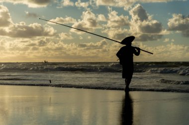 Salvador, Bahia, Brezilya - 27 Nisan 2019: Balıkçı, şafak vakti Bahia 'nın Salvador kentindeki Jaguaribe sahilinde balık tutarken görüldü..