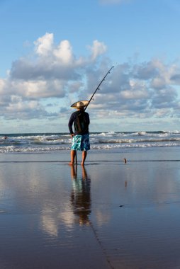 Salvador, Bahia, Brezilya - 27 Nisan 2019: Balıkçı, Salvador, Bahia 'daki Jaguaribe sahilinde şafak vakti dalgayı beklerken görüldü.