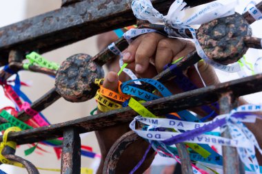 Salvador, Bahia, Brazil - December 29, 2023: Devotees are seen tying souvenir ribbons on the railing of the Senhor do Bonfim church in the city of Salvador, Bahia.