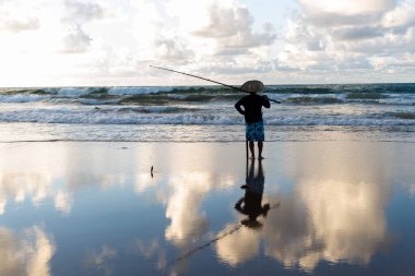 Salvador, Bahia, Brezilya - 27 Nisan 2019: Balıkçı, Salvador, Bahia 'daki Jaguaribe sahilinde şafak vakti dalgayı beklerken görüldü.