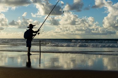 Salvador, Bahia, Brezilya - 27 Nisan 2019: Balıkçı, Salvador, Bahia 'daki Jaguaribe sahilinde şafak vakti dalgayı beklerken görüldü.