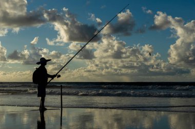 Salvador, Bahia, Brezilya - 27 Nisan 2019: Balıkçı elinde olta ve şapkayla Jaguaribe sahilinde, Bahia 'nın Salvador kentinde görüldü..