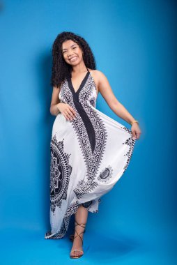 Ayakta duran, uzun elbisesini hareket ettiren güzel bir kadının portresi. Mavi arkaplanda izole.