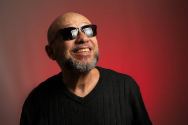 Güneş gözlüklü, kel, kendine güvenen beyaz bir adam. Kırmızı arkaplanda izole.