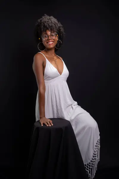 Beautiful woman, with black power hair, wearing glasses, standing wearing white clothes posing for a photo. isolated on black background.