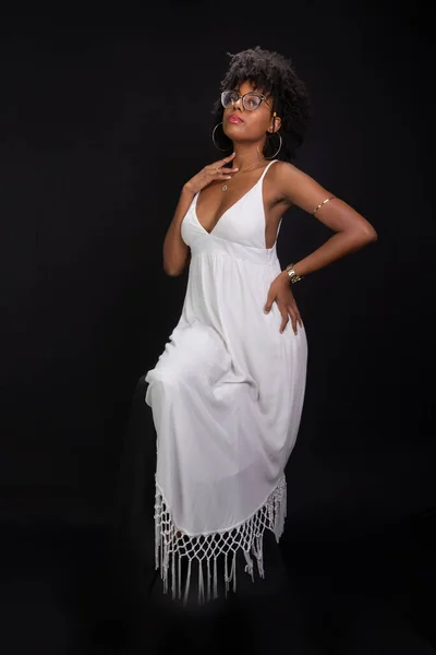 Beautiful woman, with black power hair, wearing glasses, standing wearing white clothes posing for a photo. isolated on black background.