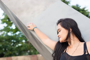 Çimento sütuna yaslanmış güzel siyah saçlı bir kadının üst kısmı. Seyahat eden kişi.