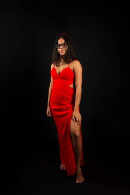 Düz saçlı, gözlüklü ve kırmızı elbiseli güzel bir kadın. Siyah arkaplanda izole.