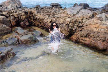 Kumsaldaki su birikintisinde güzel bir kadın, havaya su atıyor. Seyahat eden mutlu kişi.