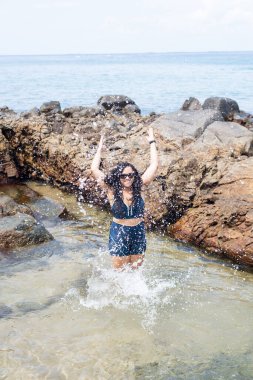 Kumsaldaki su birikintisinde güzel bir kadın, havaya su atıyor. Seyahat eden mutlu kişi.