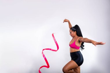 Genç jimnastikçi kadın pembe kurdeleli hareketler yapıyor. Beyaz arka plana karşı. Olimpiyat sporcusu.