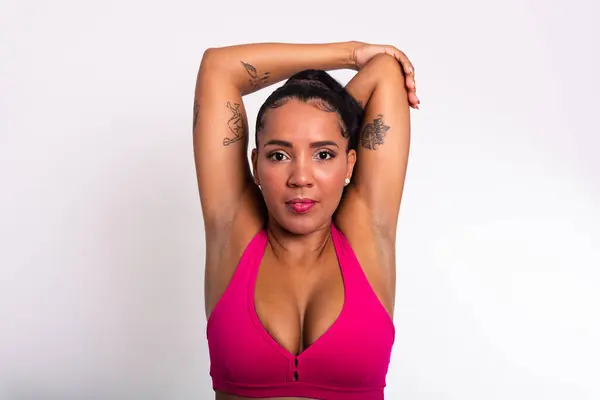 Beautiful athlete woman dressed in gym clothes, stretching with her arms behind her head. Healthy life with physical exercise.