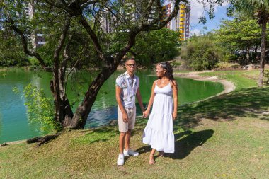 Dışarıda fotoğraf çektirmek için el ele tutuşan bir çift. Bir bebek bekliyorlar. Vahiy Çayı.