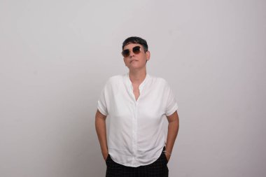 Işıklı arka planda açık renk kıyafetler ve güneş gözlüğü takan güzel kadın..