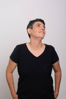 Siyah elbiseli, kısa saçlı güzel bir kadın yan tarafa bakıyor. Beyaz arkaplanda izole.