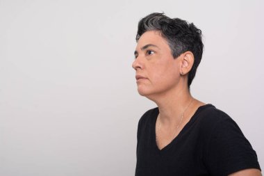 Siyah elbiseli, kısa saçlı güzel bir kadın yan tarafa bakıyor. Beyaz arkaplanda izole.