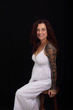 Güzel, olgun, kıvırcık kızıl saçlı, kameraya gülümseyen bir kadın. Siyah arkaplanda izole.