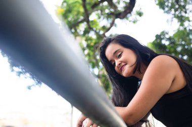 Güzel siyah saçlı kadın alüminyum korkuluklara yaslanmış kameraya bakıyor. Keyifli bir yolculukta.