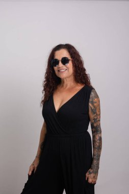 Salvador, Bahia, Brezilya - 28 Ocak 2024: Güneş gözlüğü takan ve gülümseyen siyah elbiseli güzel kıvırcık saçlı kadın. Beyaz arkaplanda izole.