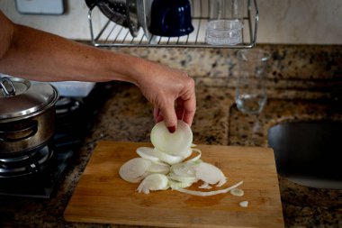 Kesme tahtasının üzerinde dilimlenmiş soğan tutarken. Yiyecek çeşnisi.