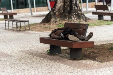 Salvador, Bahia, Brezilya - 05 Ocak 2024: Evsiz bir adam, Bahia 'nın Salvador kentindeki Comercio mahallesindeki ahşap bir bankta uyurken görüldü..