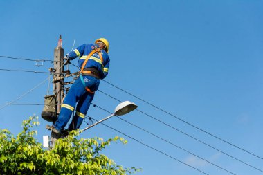 Aratuipe, Bahia, Brezilya - 30 Mayıs 2015: Elektrik direğinin tepesinde tamirat yapan bir teknisyen. Bahia 'nın Aratuipe şehrinin Maragogipinho ilçesi.