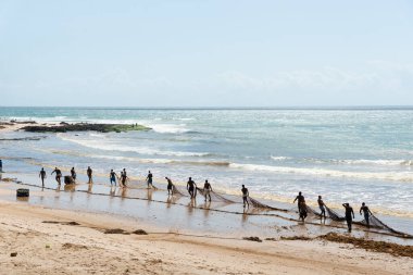 Salvador, Bahia, Brezilya - 25 Aralık 2018: Balıkçılar, Bahia 'nın Salvador kentindeki Boca do Rio plajında büyük bir balık ağı taşırken görüldü..