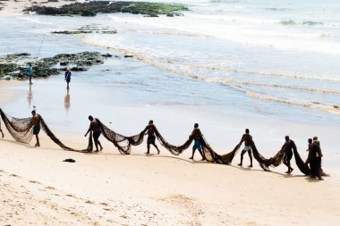 Salvador, Bahia, Brezilya - 25 Aralık 2018: Balıkçılar büyük bir balık ağı taşıyorlar. Sıraya girerler. Boca do Rio Beach Salvador, Bahia 'da..