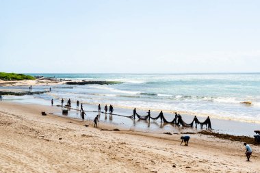 Salvador, Bahia, Brezilya - 25 Aralık 2018: Balıkçılar büyük bir balık ağı taşıyorlar. Sıraya girerler. Boca do Rio Beach Salvador, Bahia 'da..