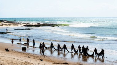 Salvador, Bahia, Brezilya - 25 Aralık 2018: Balıkçılar, Bahia 'nın Salvador kentindeki Boca do Rio plajında büyük bir balık ağı taşırken görüldü..