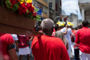 Salvador, Bahia, Brezilya - 4 Aralık 2023: Katolik inananlar, Salvador, Bahia şehrinde Santa Barbara onuruna düzenlenen geçit töreninde bir aziz figürü taşıyan bir yürüyüşçü olarak görüldü..