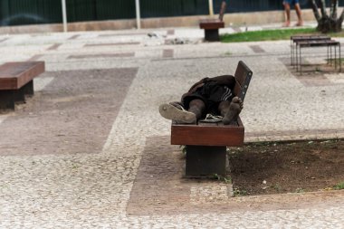 Salvador, Bahia, Brezilya - 05 Ocak 2024: Evsiz bir adam, Bahia 'nın Salvador kentindeki Comercio mahallesindeki ahşap bir bankta uyurken görüldü..