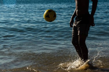 Salvador, Bahia, Brezilya - 09 Mart 2019: Salvador, Bahia 'da Ribirya plajının kenarında genç bir adamın futbol oynadığı görüldü.