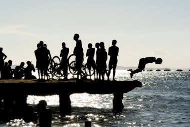 Salvador, Bahia, Brezilya - 09 Mart 2019: Genç insanlar, siluet içinde, Salvador, Bahia 'daki Crush Köprüsü' nden atlarken ve eğlenirken görülüyor..