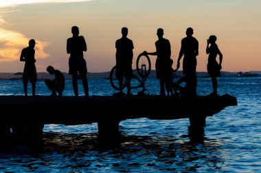 Salvador, Bahia, Brazil - March 09, 2019: Dozens of young people, in silhouette, are seen on top of the Crush bridge having fun. City of Salvador, Bahia. clipart
