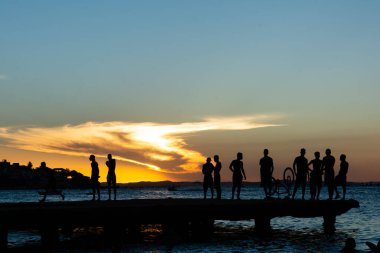 Salvador, Bahia, Brezilya - 09 Mart 2019: Gençler ve siluetler gün batımında Bahia 'nın Salvador kentindeki Crush Köprüsü' nün tepesinde birlikte eğlenirken görüldüler..