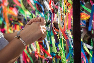 Salvador, Bahia, Brezilya - 29 Aralık 2023: Bahia 'nın Salvador kentindeki Sinyor do Bonfim kilisesinin korkuluklarına hatıra kurdeleleri bağlayan turist elleri.