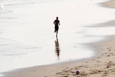 Salvador, Bahia, Brezilya - 14 Şubat 2019: Bir adam görüldü, siluet içinde, öğleden sonra Salvador, Bahia 'da plajda koşarken.