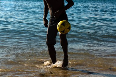 Salvador, Bahia, Brazil - March 09, 2019: A young man is seen playing beach soccer on Riberia beach in the city of Salvador, Bahia. clipart