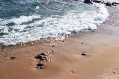 Sahilin kenarında küçük dalgalar. Güneşli gün, sakin deniz suyu.