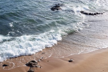 Sahilin kenarında küçük dalgalar. Güneşli gün, sakin deniz suyu.