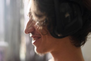 Pencere ışığına karşı mutlu ve gülümseyen bir yetişkinin profili. Evde portre.