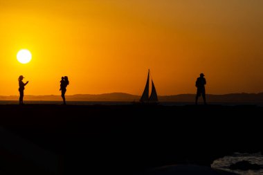 Salvador, Bahia, Brezilya - 15 Mart 2019: İnsanlar, siluet içinde Porto da Barra rıhtımında, Salvador, Bahia şehrinde günbatımının keyfini çıkarırken görüldüler..